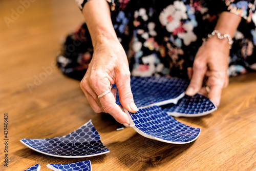Close-up of woman picking up a broken plate  photo