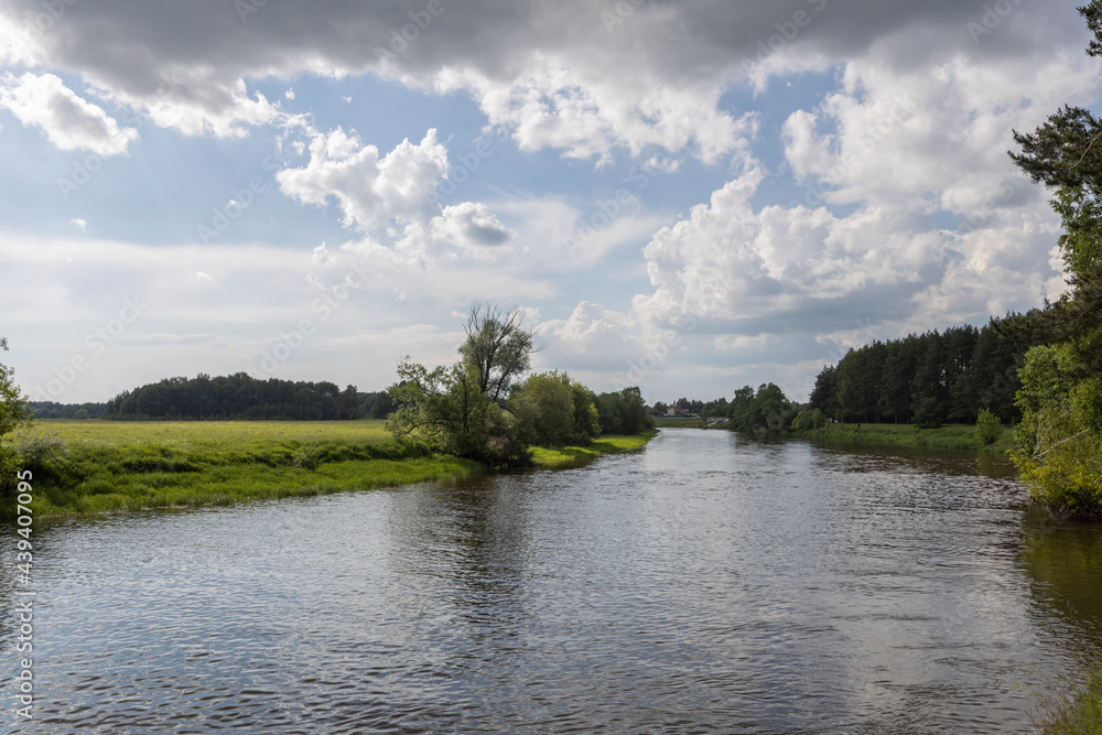 River landscape with reflections of clouds and forest in the water. In summer. Sunny day. No one. Natural island.Summer rural landscape on a sunny day. lush vegetation, beautiful clouds in the sky
