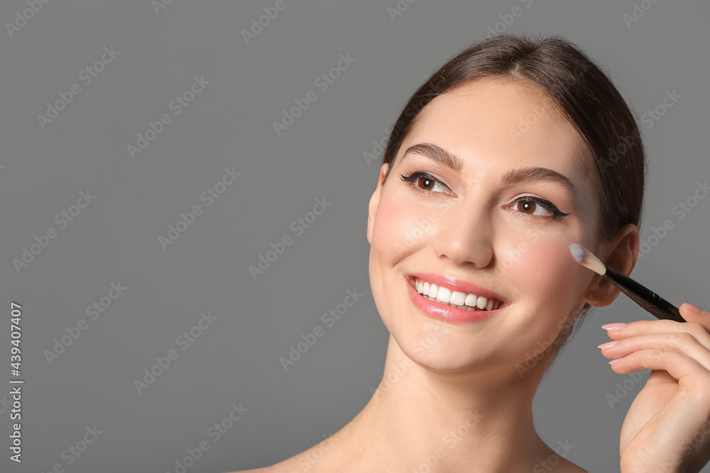 Beautiful young woman with makeup brush on grey background, closeup Beautiful young woman with makeup brush on grey background, closeup