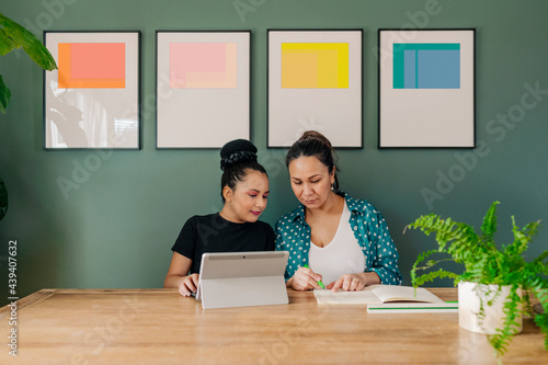 Woman teaching girl and sharing table  photo