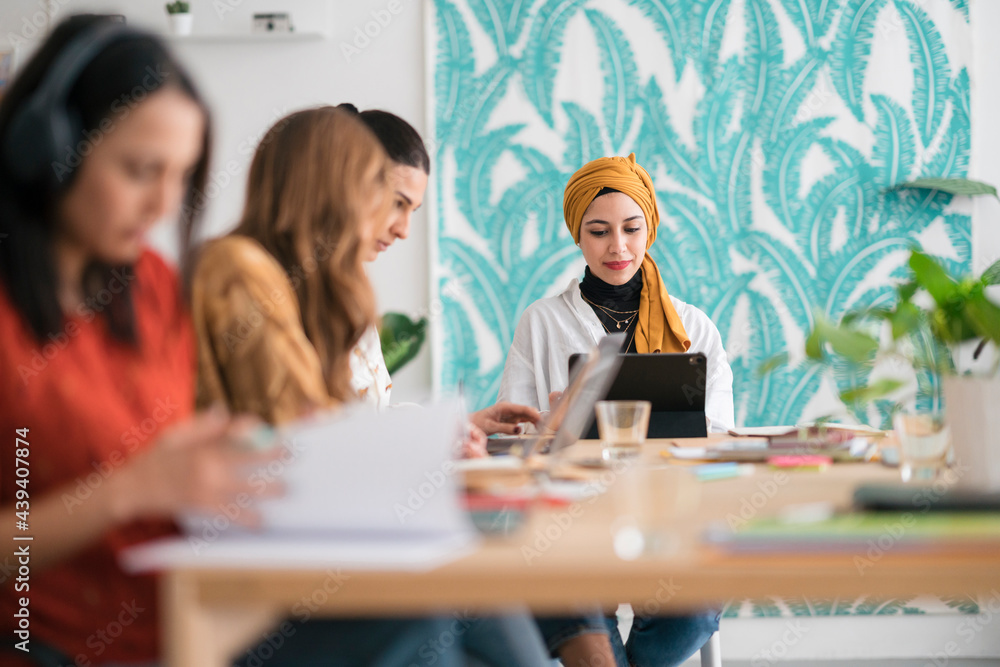 Multiracial team of smart female entrepreneurs working in office using various gadgets Multiracial team of smart female entrepreneurs working in office using various gadgets