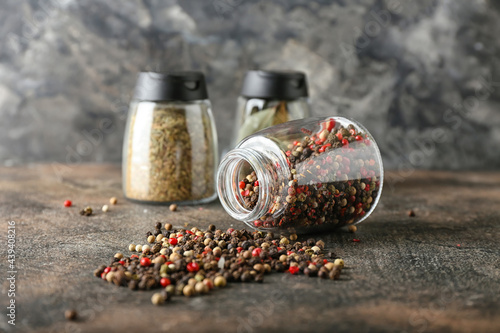 Overturned jar with mixed peppercorns on grunge background