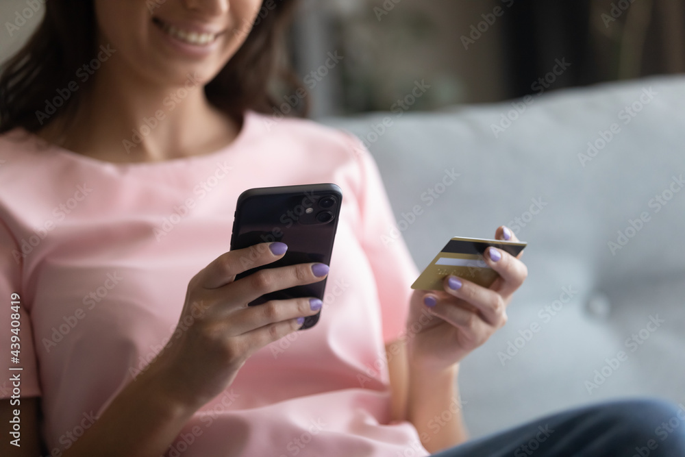 Close up smiling Arabian woman holding credit card and smartphone in hands, paying online in internet store, shopping at home, satisfied positive customer browsing banking service, checking balance Close up smiling Arabian woman holding credit card and smartphone in hands, paying online in internet store, shopping at home, satisfied positive customer browsing banking service, checking balance
