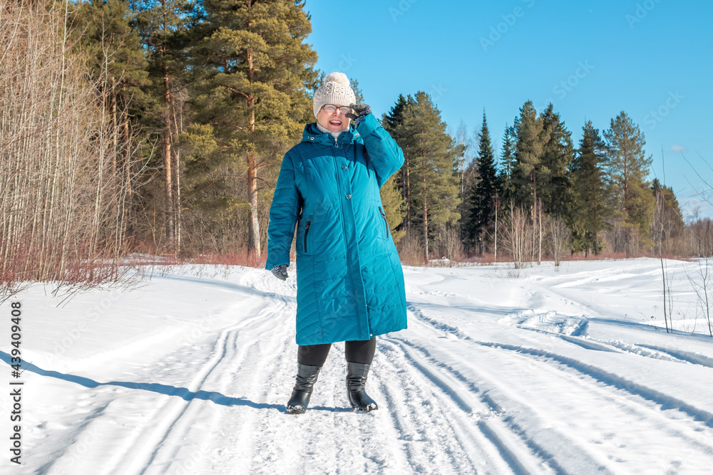 Grandmother walks in nature in winter. Cheerful elderly woman.