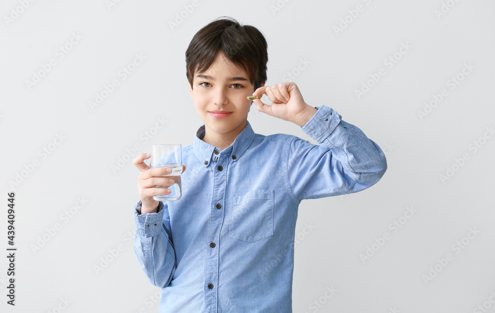 Little boy with fish oil pill on light background Little boy with fish oil pill on light background