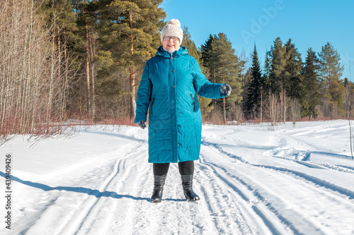 Grandmother walks in nature in winter. Cheerful elderly woman.