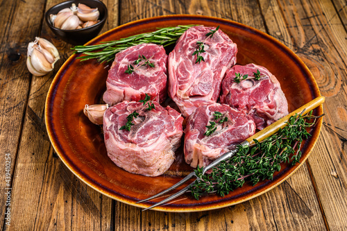 Mutton lamb neck meat on a rustic plate with thyme and rosemary. wooden background. Top view