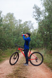 Young man drinking water on his bike on a forest road, active lifestyle.