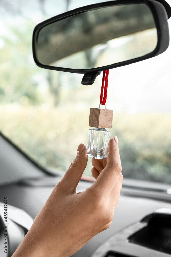 Female hand with air freshener hanging in car, closeup