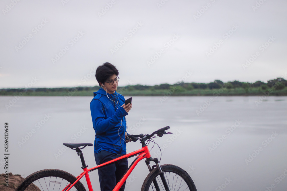 Young cyclist with headset using his smart phone outdoors. Young cyclist with headset using his smart phone outdoors.