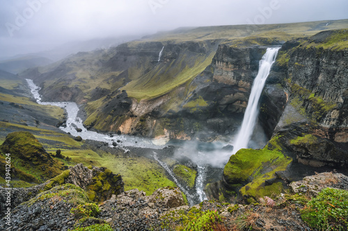 Highlands of Iceland. Haifoss waterfall and River Fossa stream in the valley. Hills and cliffs are coverd by green moss.