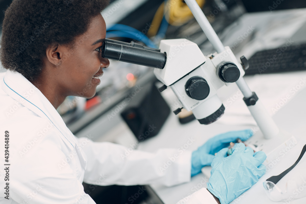 Scientist african american woman engineer working in laboratory with electronic tech instruments and microscope. Research and development of electronic devices by color black woman. Scientist african american woman engineer working in laboratory with electronic tech instruments and microscope. Research and development of electronic devices by color black woman.