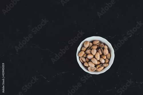 Pistachios in a white plate on a dark background