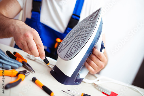 Fotografija Close up photo of concentrated young man while he is fixing damaged iron on his