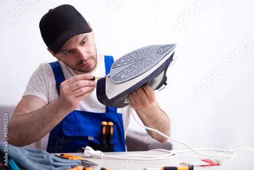 Photography Close up photo of concentrated young man while he is fixing damaged iron on his