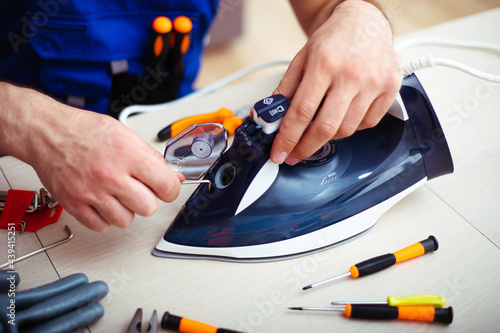Fotografija Close up photo of concentrated young man while he is fixing damaged iron on his
