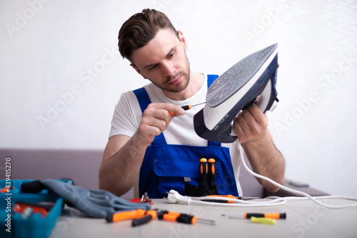 Φωτογραφία Close up photo of concentrated young man while he is fixing damaged iron on his