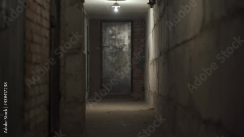 Wallpaper Mural First person view moving straight down a narrow empty dark narrow corridor with concrete walls under the ground with dim light. Underground catacombs of World War II. Metal door at the end of corridor Torontodigital.ca