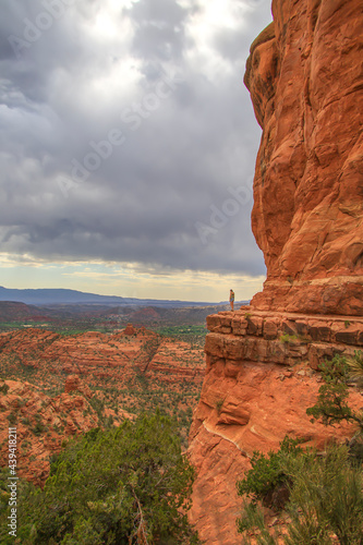 Woman standing on a cliff next to red rocks