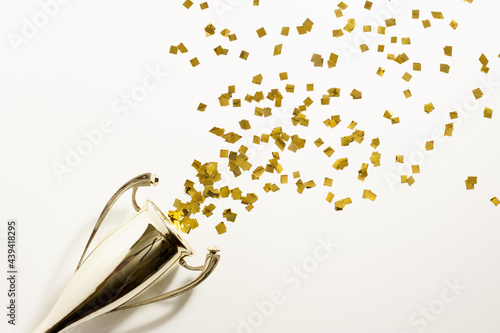 Golden cup and explosion of confetti on the light background