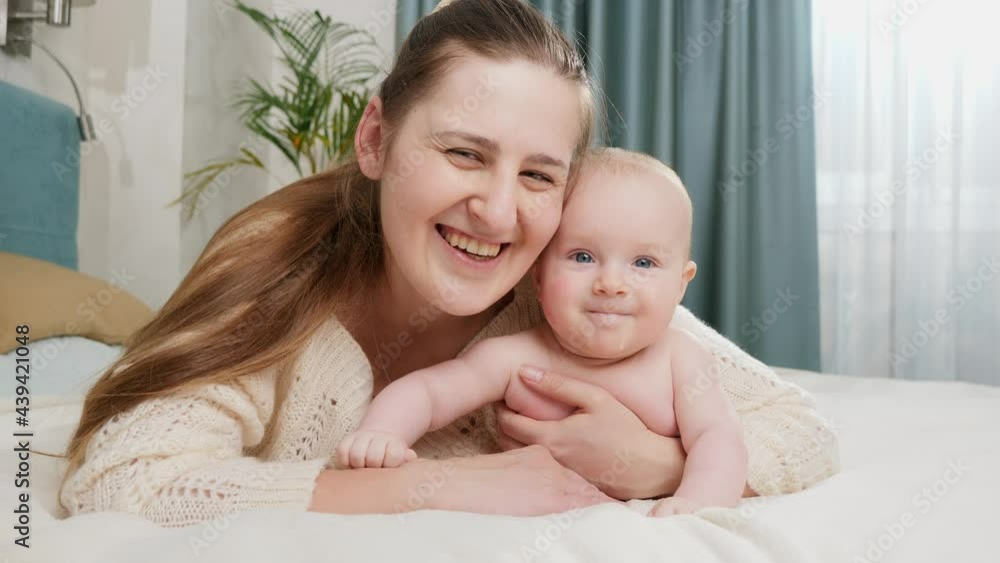 Smiling little baby boy with happy mother lying in bed and looking in camera. Concept of parenting ,baby care and family happiness Smiling little baby boy with happy mother lying in bed and looking in camera. Concept of parenting ,baby care and family happiness