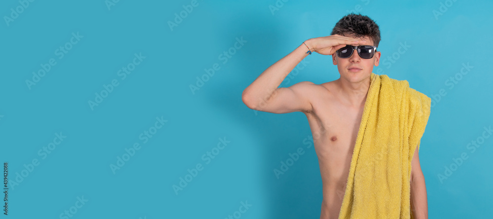 isolated teen boy looking to the horizon with sunglasses and beach towel isolated teen boy looking to the horizon with sunglasses and beach towel