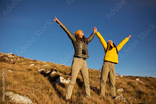 Excited female hikers with raised hands