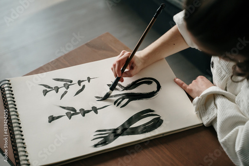Young woman writing japanese kanji characters with a brush and ink photo