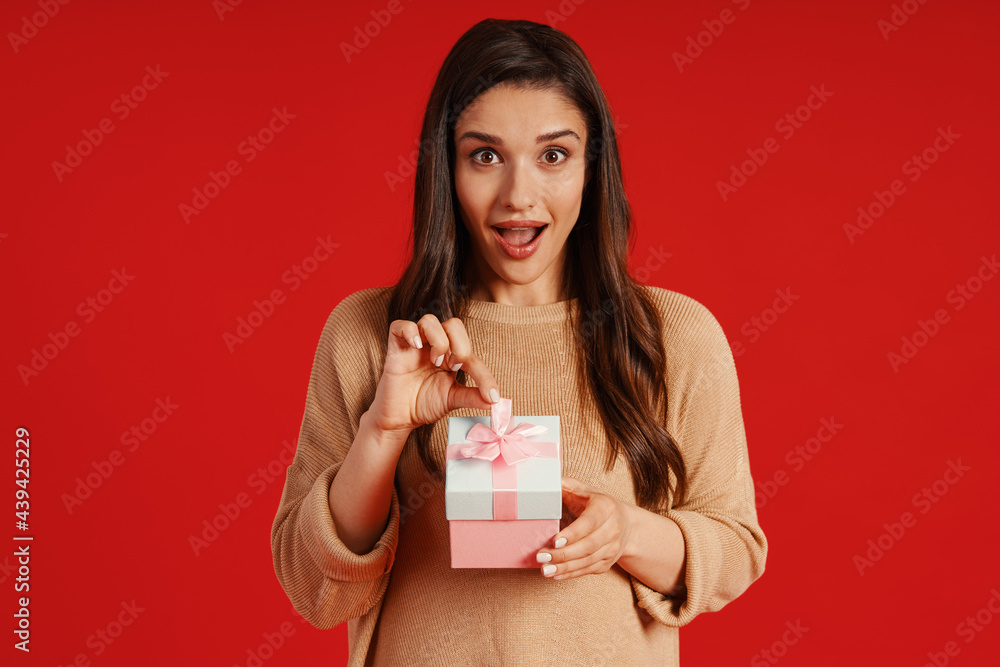 Attractive young woman in casual clothing holding a present and smiling Attractive young woman in casual clothing holding a present and smiling