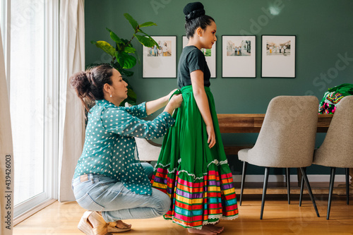Mother helping daughter to dress up for a Mexican perfomance photo
