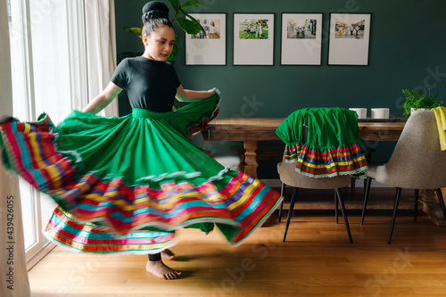 Tween girl trying on her traditional Mexican folkloric skirt at home