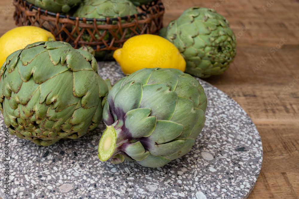 Obraz premium Fresh ripe green artichokes heads with yellow lemons ready to cook