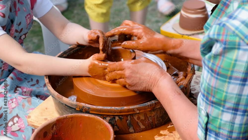 Woman and girl making ceramic pot in pottery Female hands on