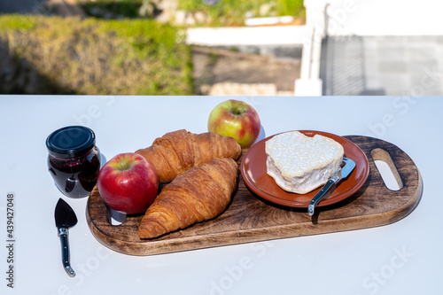 French breakfast with fresh baked croissants and cheeses from Normandy, heart-shaped neufchatel served outdoor with nice city view photo