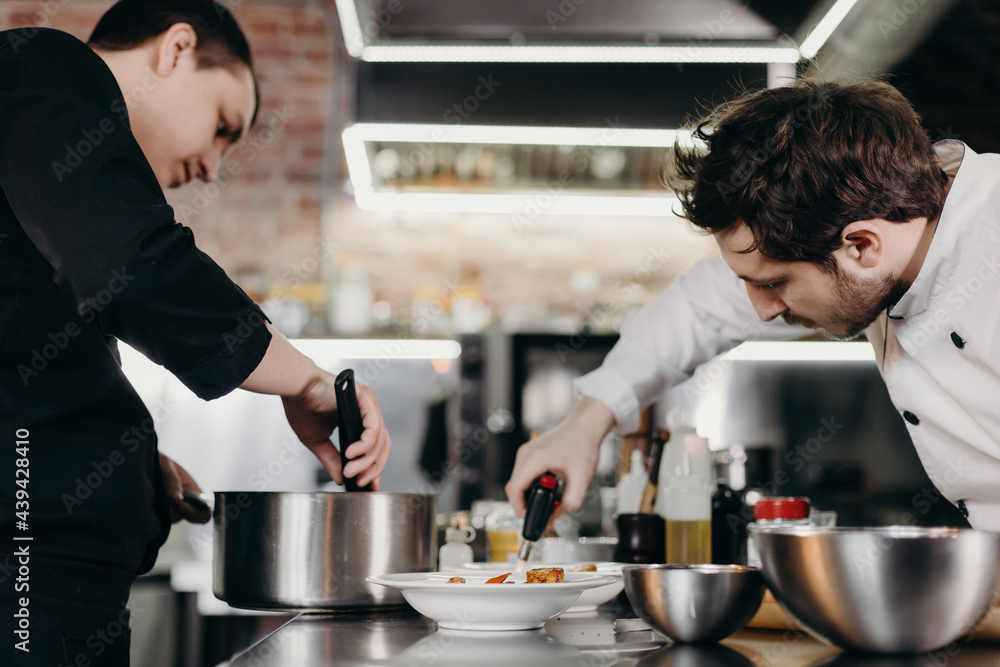 Chef with colleague serving meal in kitchen Chef with colleague serving meal in kitchen