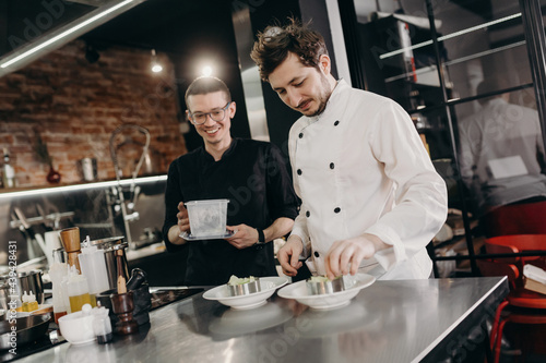 Chef with apprentice preparing dish in restaurant photo