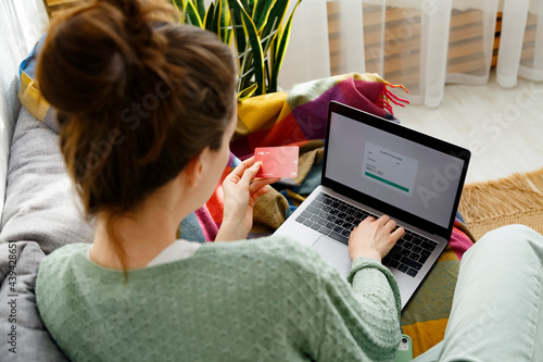 Woman entering credential during online shopping on laptop