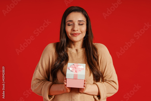 Attractive young woman in casual clothing holding a present and smiling © gstockstudio
