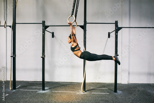 Muscular sportswoman swinging on rings in gym  photo