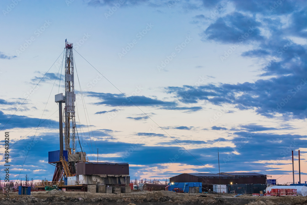 A site in the northern tundra at an oil and gas field. Drilling rig for drilling wells. Infrastructure and drilling equipment for drilling operations. Beautiful expressive sky