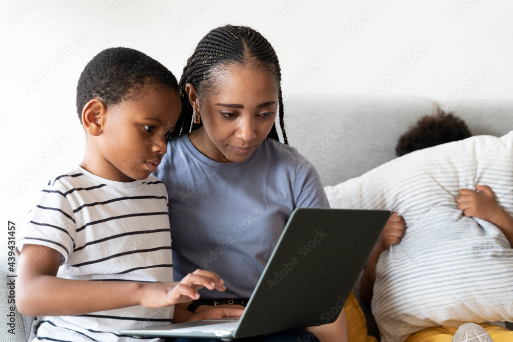 Boy using laptop with his mother at home. Boy using laptop with his mother at home.