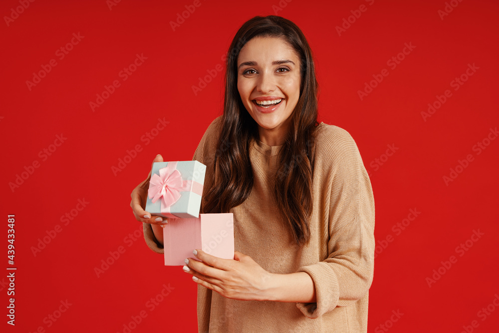 Surprised young woman in casual clothing holding a present and smiling Surprised young woman in casual clothing holding a present and smiling