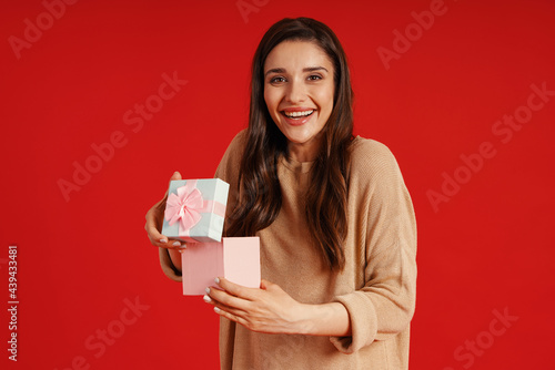 Surprised young woman in casual clothing holding a present and smiling © gstockstudio