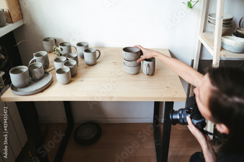 Female artisan photographs ceramic products. photo