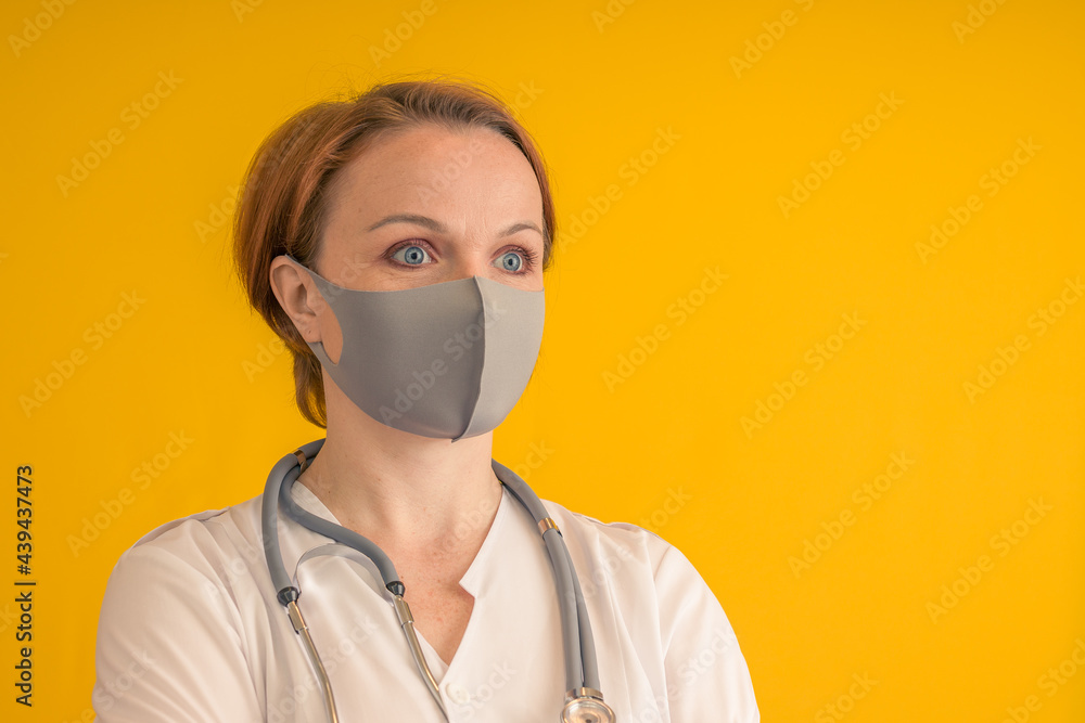 The doctor in a gray mask with a stethoscope. On a yellow background. The doctor in a gray mask with a stethoscope. On a yellow background.