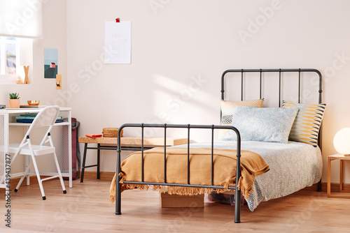 Tidy metal bed with cushions. photo