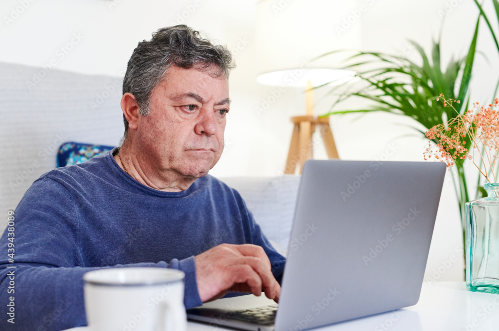 Mature man browsing online with a laptop Mature man browsing online with a laptop