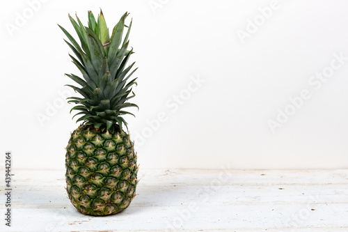 Fresh organic green and yellow pineapple on a wooden table isolated on white with a shallow depth of field and copy space
