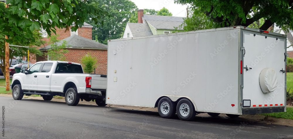 White pickup truck and large utility trailer parked on residential city street. - obrazy, fototapety, plakaty 