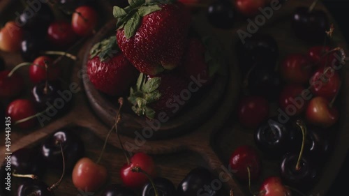 menazhnitsa with red strawberries and cherries on a dark background. Wooden plate made with compartments for snacks photo